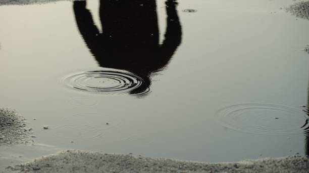 istock Reflection of the man in the puddle with raindrops 1437269490
