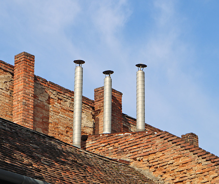 The Gable of a brick house with brick chimney in bright sunlight, against a deep blue sky.