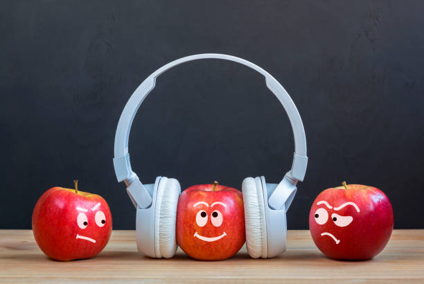 istock envy Creative concept. Abstract image with apples. One Apple in headphones standing in crowd stands out. 1437273732