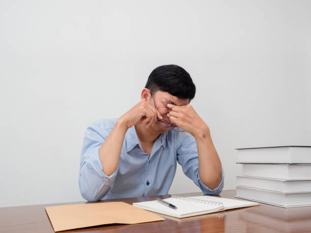 istock Young businessman sit at table take off his glasses feels tried about working 1437274210