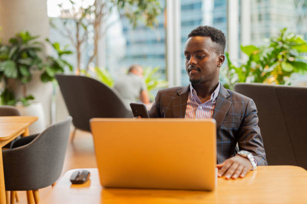 istock Black businessman using laptop computer at coffee shop 1437276125