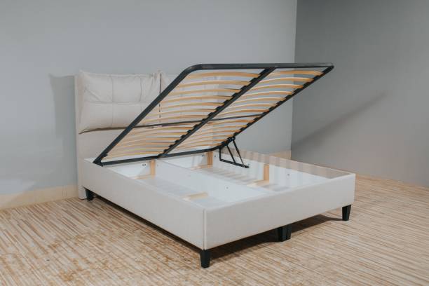 istock Beige bed with a storage space revealed by lifting the wooden slatted base 1437276252