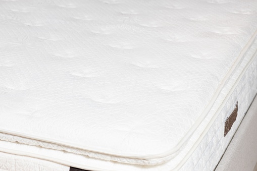 A closeup shot of a quilted white mattress and topper with soft flowers pattern