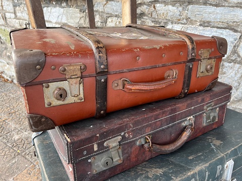 An old closed brown fiber suitcase with sticking out dollar banknotes. Laying on side and isolated on white background.