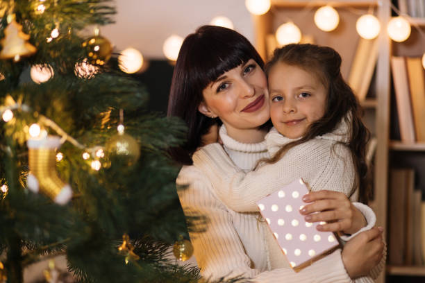 istock Happy mom hugging small daughter with Christmas and congratulate her with gift. 1437280548