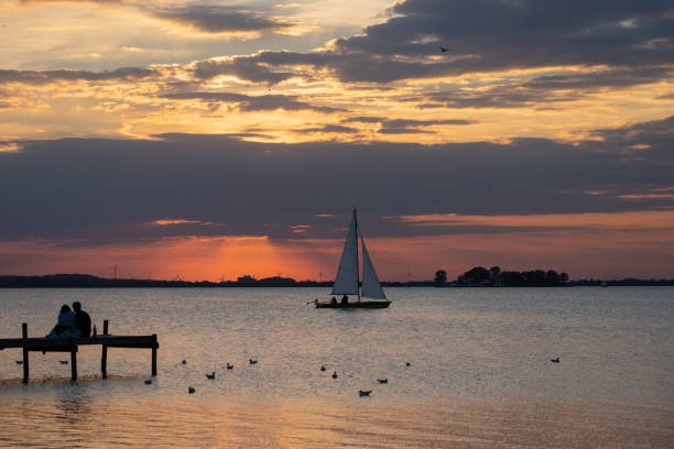 vista posteriore sulla coppia in siluetta con barca a vela e isola sul lago - steinhuder meer foto e immagini stock