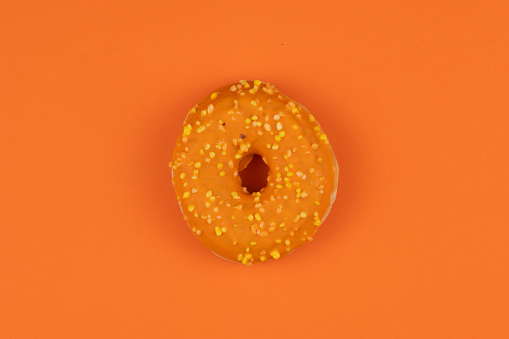 Sweet tasty doughnut with sprinkles on colour background