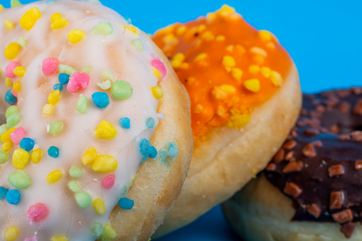 Sweet tasty doughnut with sprinkles on blue background