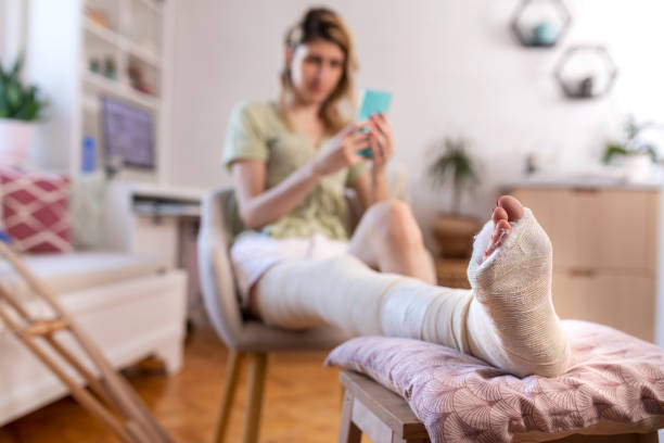 istock Young woman with leg in plaster  using mobile phone 1437287645
