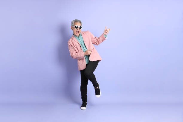 Active Senior Man The 40s adult Asian man stnading on the purple background with smart casual clothes. air guitar stock pictures, royalty-free photos & images