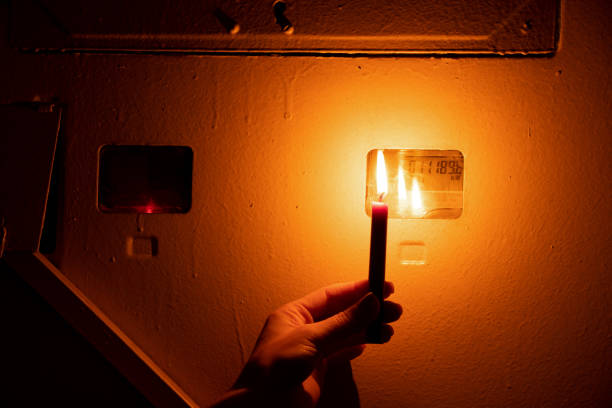 istock A woman's hand holds a candle next to a shield with a meter in an apartment, Ukraine without electricity due to war, power outages 2022 1437292040