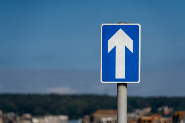 one way sign set against a blue sky - one way street sign imagens e fotografias de stock