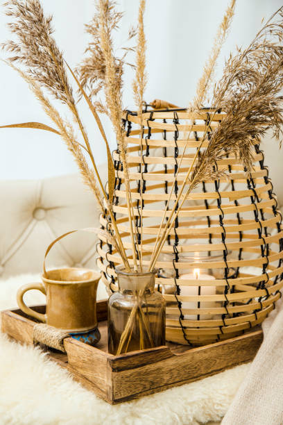 istock Cozycore or cottagecore concept, warm soft brown beige interior design objects. Cozy wool plaid on sofa, candle burning in wood lantern, tea cup on wood serving tray. Warm color photo manipulation. 1437303917
