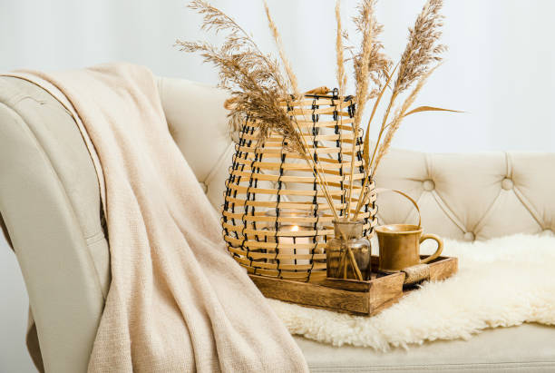 istock Cozycore or cottagecore concept, warm soft brown beige interior design objects. Cozy wool plaid on sofa, candle burning in wood lantern, tea cup on wood serving tray. Warm color photo manipulation. 1437303929