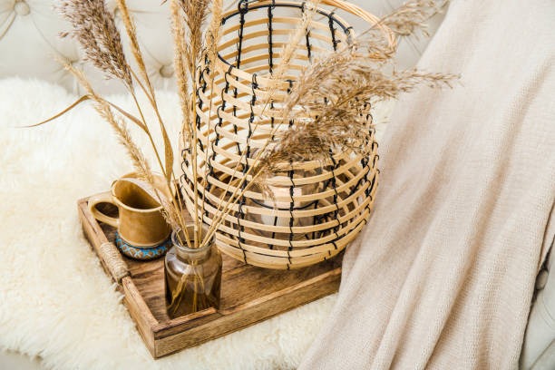 Cozycore or cottagecore concept, warm soft brown beige interior design objects. Cozy wool plaid on sofa, candle burning in wood lantern, tea cup on wood serving tray. Warm color photo manipulation. concepto cozycore o cottagecore, cálidos objetos de diseño de interiores de color beige marrón suave. acogedora lana a cuadros en el sofá, vela encendida en linterna de madera, taza de té en bandeja de servir de madera. manipulación de fotos en color