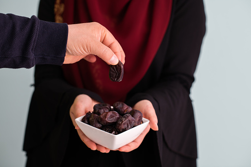 modern muslim woman holding a plate full of sweet dates on iftar time in ramadan kareem islamic healthy food concept. High quality photo