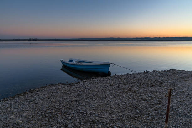 sunset over lake budeasa in central romania with a wooden rowboat tied up on the rocky beach - transsylvania imagens e fotografias de stock
