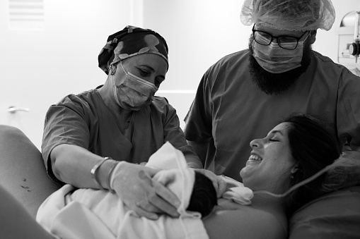 Mother giving birth to a baby boy. Parent and infant first moments of bonding. Father and nurse hekping in the process. Buenos Aires. Argentina