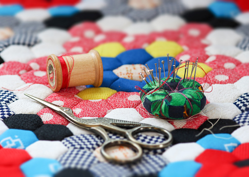 Quilting supplies on a colorful hexagon mosaic patterned quilt. The creative sewer.