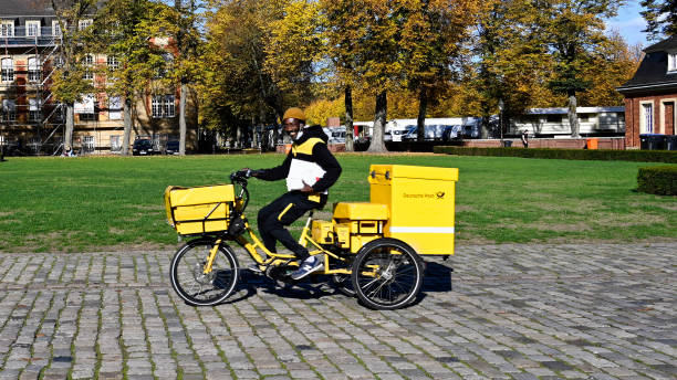 Münster, Germany, October 18, 2022 - Deutsche Post letter carrier delivering mail with an electric bicycle.