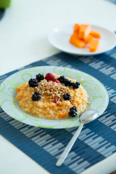 cup of freshly brewed pumpkin porridge with berries on the table. healthy food idea stock photo