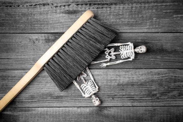 The brush sweeps two skeletons and bones from the wooden floor. The concept of cleaning up after a murder.