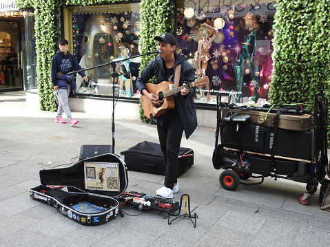28th October 2022, Dublin, Ireland. Busker singing and playing guitar outside Brown Thomas department store on Grafton Street, Dublin city centre.