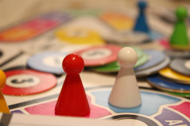 istock Red and White Pawns on a Game Board with Multiple Cards on Top 1437320106