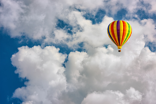 A lonely hot air balloon floats above the clouds.