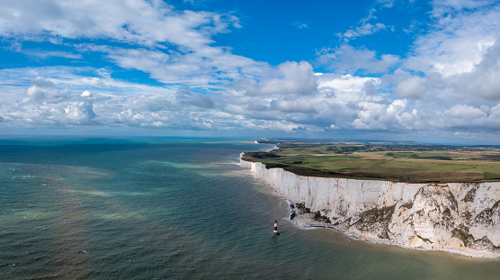 A panorama view of the Beachy Head Lighthouse in the English Channel and the white cliffs of the Jurassic Coast