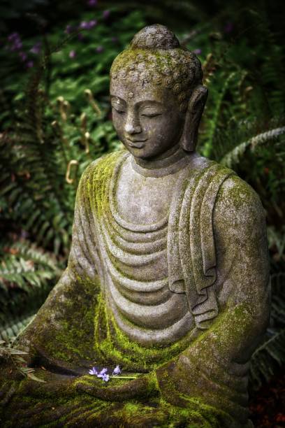 istock Vertical shot of a Buddha statue with moss on top and greenery on the background 1437321972