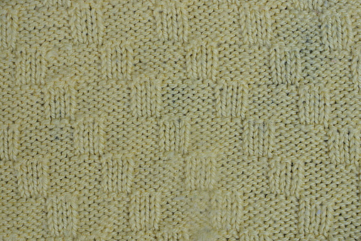 green woolen texture of a sweater fabric with a pattern on clothes