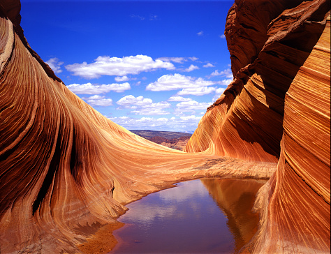 View to the north at the entrance of The Wave. Sandstone swirls, water, and the clouds offer an eye-popping play.