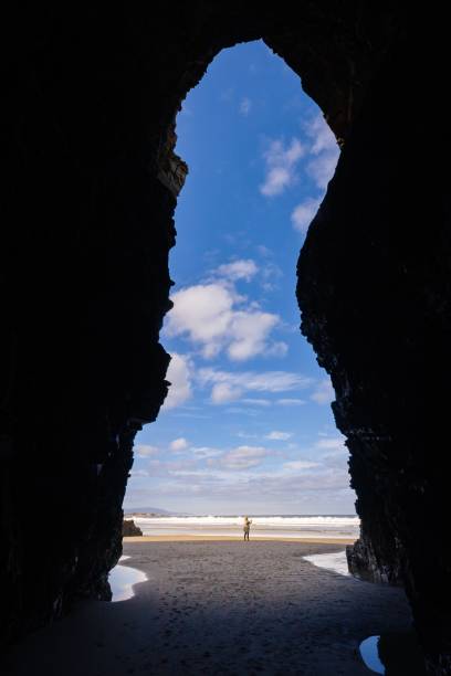 istock Vertical shot from inside a cave with a person standing on the beach 1437332669