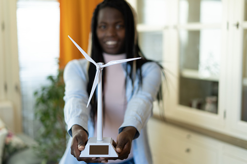 Young afro-American woman holding a windmill as concept for renewable energy.