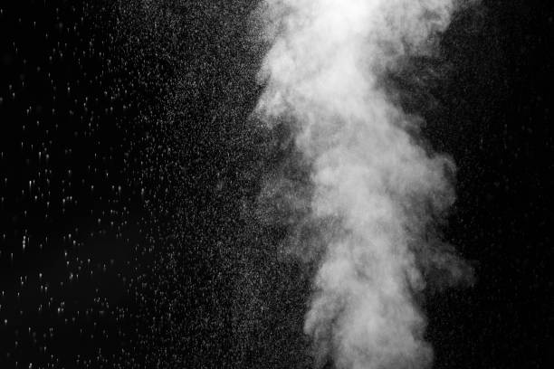 Stream of white curly steam with water drops on a black background. Sprayed water. Splashes and drops of water