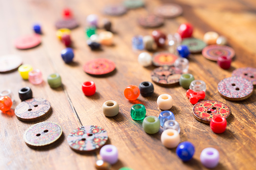 LV Colorful buttons and beads on a wooden craft table.  Great background images.  Hobbies.
