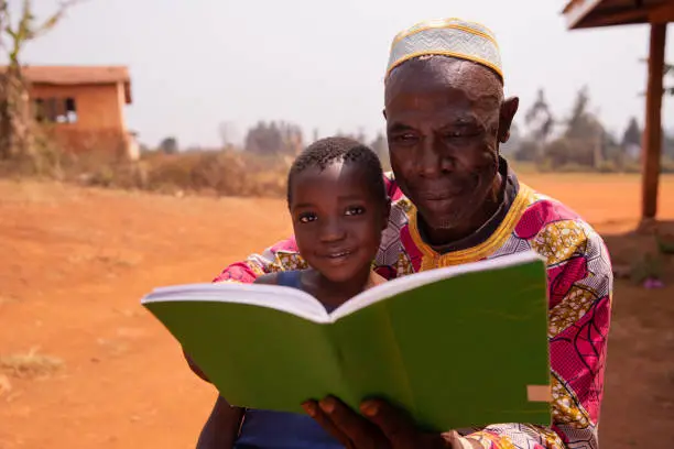 African grand father educating his grandson outdoor under the sun. Education concept.