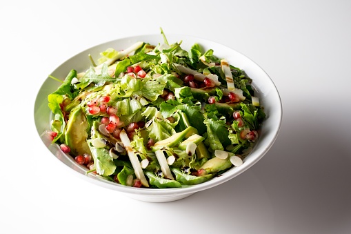 A delicious salad with lettuce avocadoes, jicama and pomegranates seasoned with salt and pepper