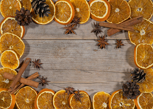 Woman decorating fresh tangerine with cloves at light blue wooden table, top view