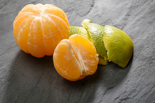 Group of half, peeled and whole tangerines on the stone background, still life concepts
