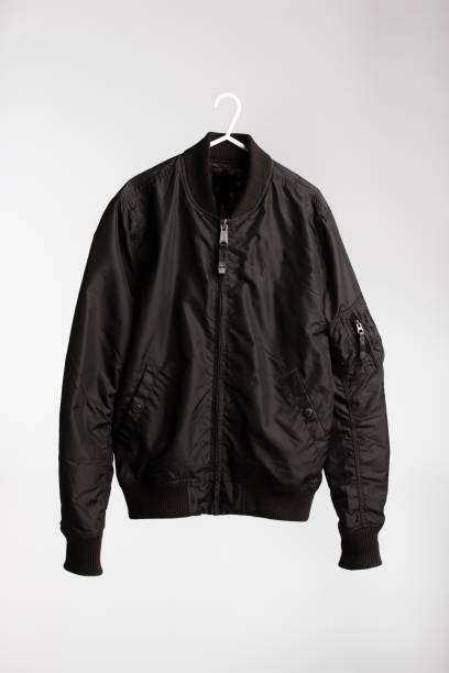 istock Black jacket on cloth hanger with white wall in the background 1437350653