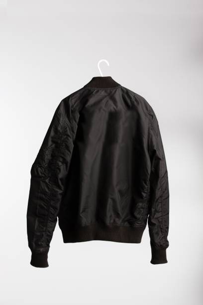 istock Black jacket on cloth hanger with white wall in the background 1437350747