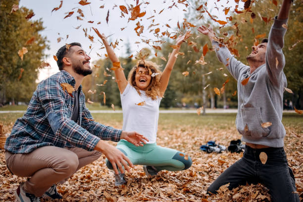 istock Friends having fun throwing leaves in the air 1437351465