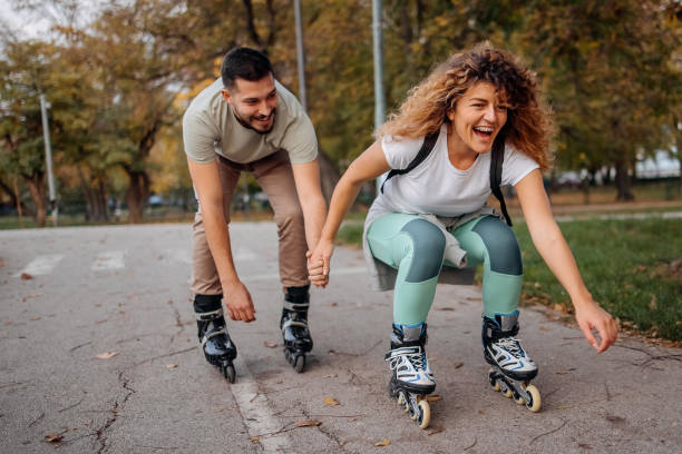 We ride together Loving couple is riding roller skates in the park inline skating stock pictures, royalty-free photos & images