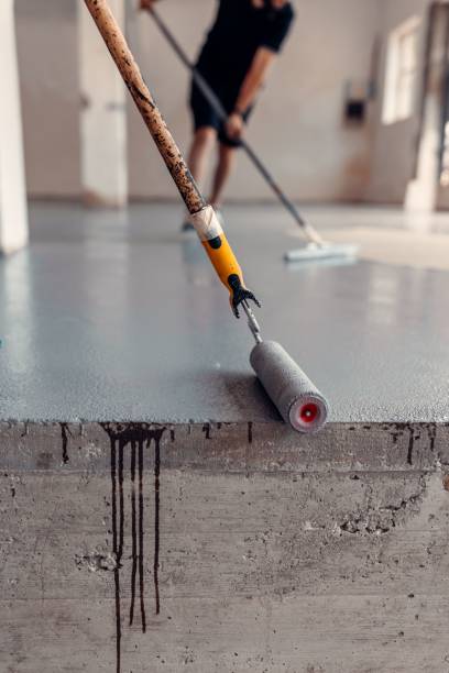 istock Vertical close up shot of two construction workers applying grey epoxy resin in an industrial hall 1437357390