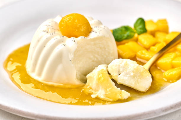istock Macro spoon with piece of panna cotta with natural vanilla pod, mango syrup and mint, selective focus 1437366076
