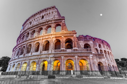 Coliseum by night with full moon in Roma, Italy