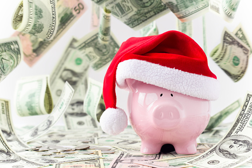 Pink piggy bank in Santa hat with money falling flying levitating around