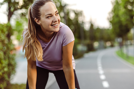 A smiling athlete woman taking a break during jogging in a residential area
